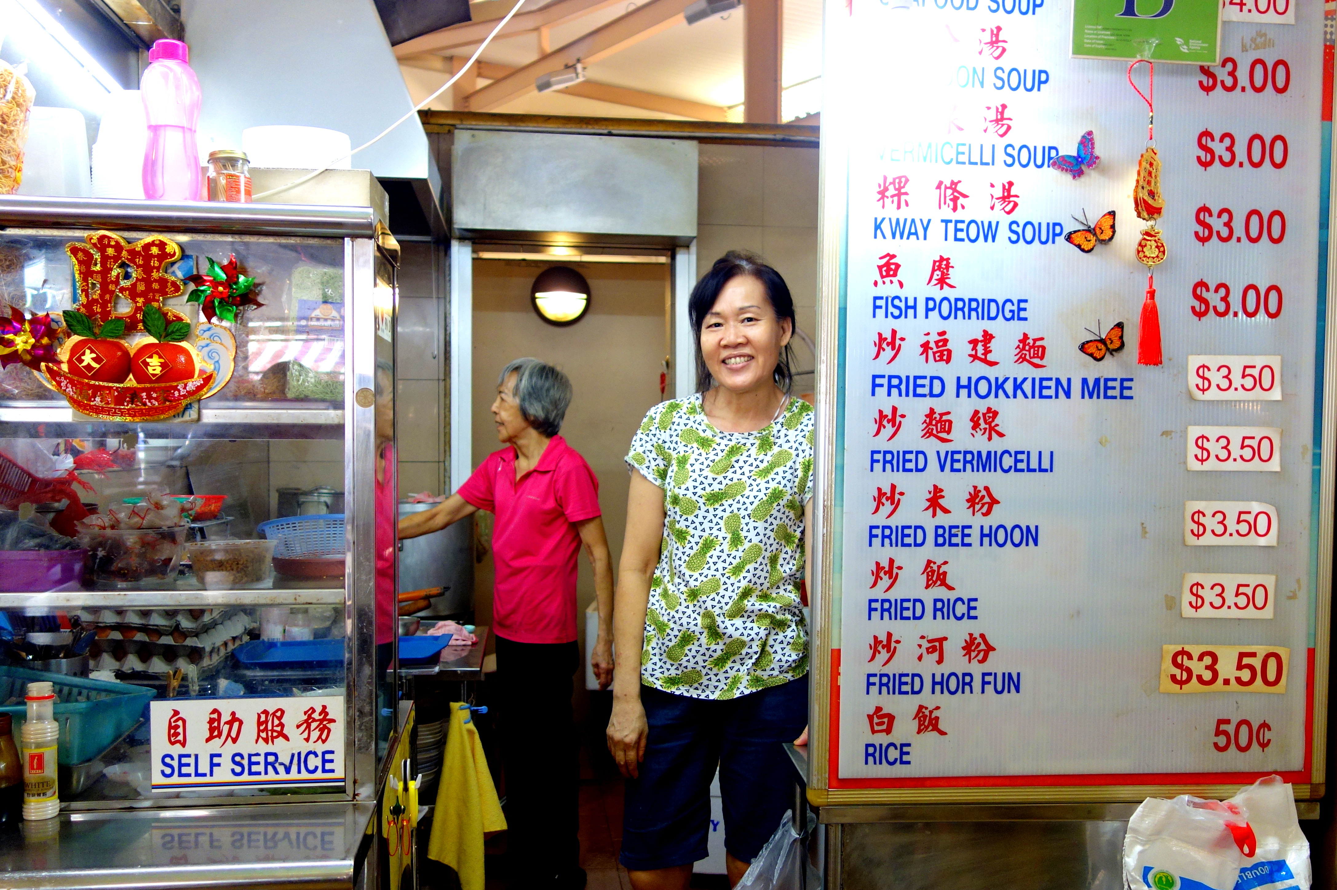 Hawker selling hor fun, fish porridge, and other Singaporean food at a hawker centre at Holland Village | ShopkeeperStories.com